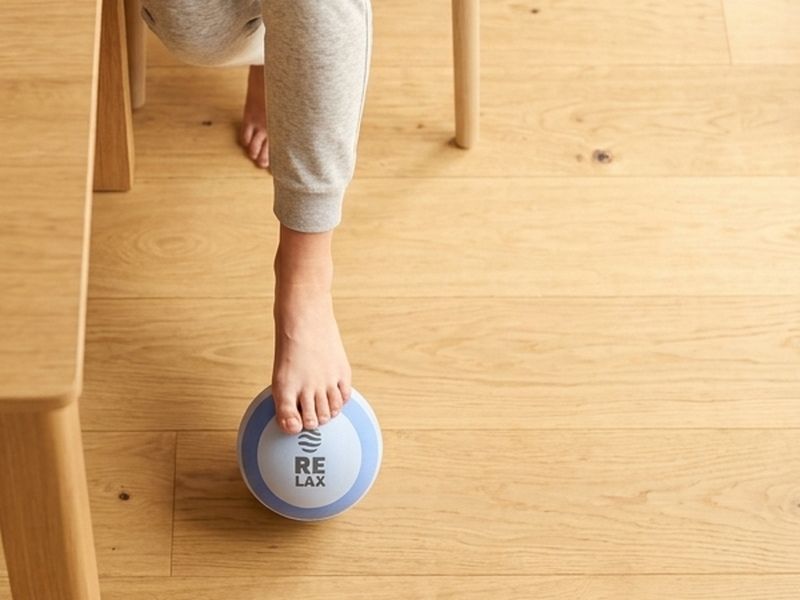 Bare foot rolling the ball on a wooden floor